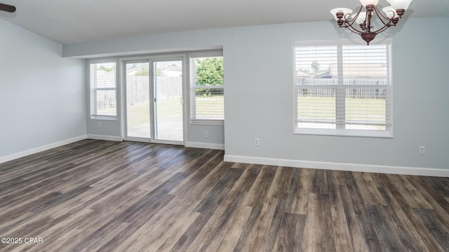 unfurnished room featuring baseboards, dark wood-style floors, and an inviting chandelier