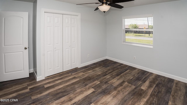 unfurnished bedroom featuring ceiling fan, baseboards, dark wood-style flooring, and a closet