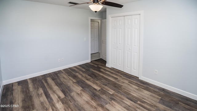 unfurnished bedroom featuring baseboards, dark wood-type flooring, visible vents, and a closet