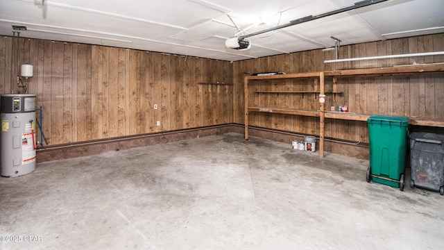 garage featuring water heater, wood walls, and a garage door opener