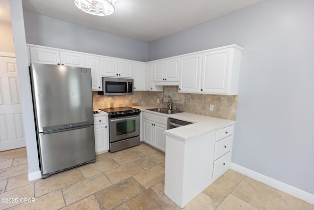 kitchen featuring tasteful backsplash, a sink, stone tile floors, stainless steel appliances, and light countertops