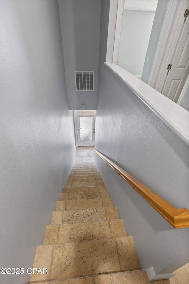 stairway featuring stone tile floors and visible vents