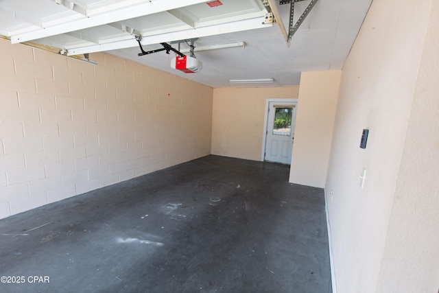 garage featuring concrete block wall and a garage door opener