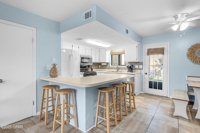 171 Damon Cir, Panama City Beach, FL 32407 - kitchen featuring black gas range oven, stainless steel microwave, freestanding refrigerator, a sink, and a peninsula