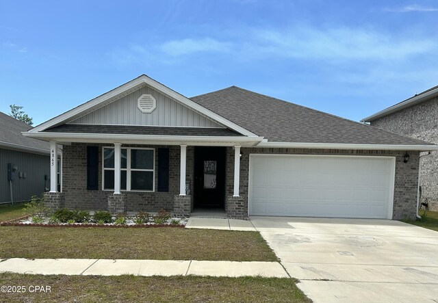 craftsman inspired home with concrete driveway, a shingled roof, covered porch, an attached garage, and brick siding