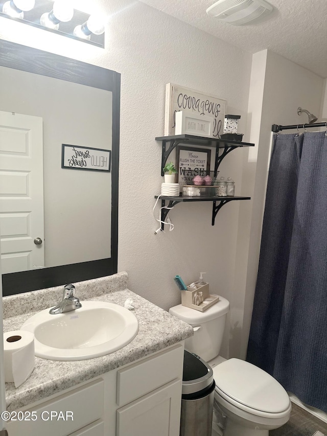 full bathroom featuring toilet, curtained shower, vanity, visible vents, and a textured ceiling