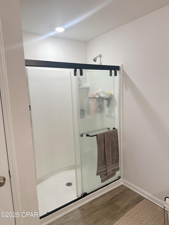 full bathroom with a stall shower, wood finished floors, and baseboards
