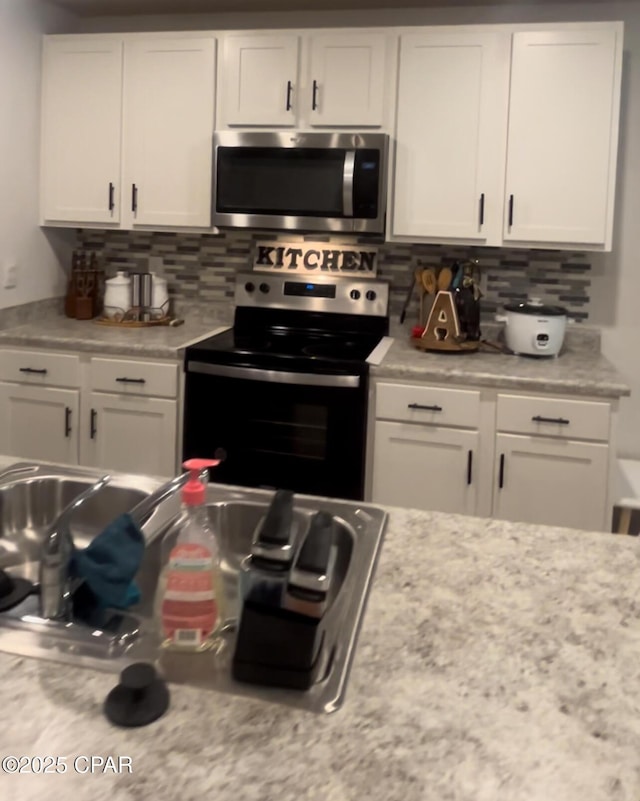 kitchen with white cabinets, appliances with stainless steel finishes, and decorative backsplash