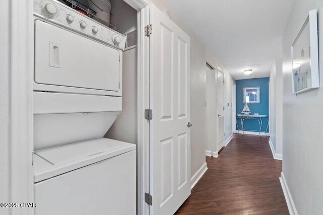 9900 S Thomas Dr Unit 819, Panama City Beach, FL 32408 - clothes washing area featuring dark wood-type flooring, laundry area, baseboards, and stacked washing maching and dryer