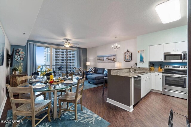 9900 S Thomas Dr Unit 819, Panama City Beach, FL 32408 - kitchen featuring a peninsula, white cabinets, a sink, dark wood finished floors, and stainless steel appliances
