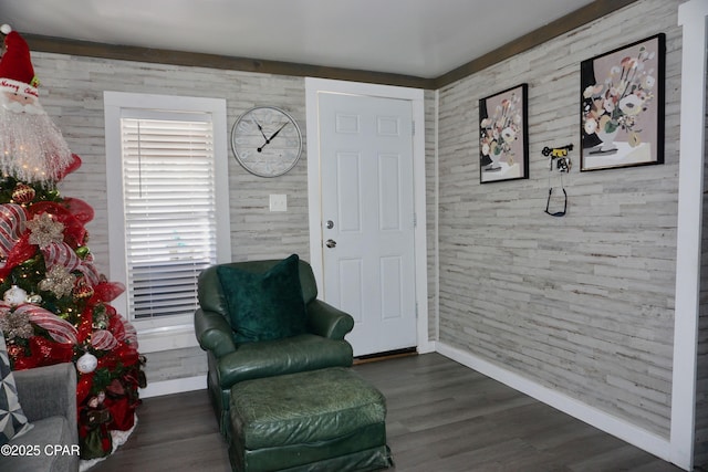 sitting room with wood walls, wood finished floors, and baseboards