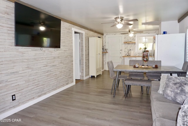 dining area with baseboards, a ceiling fan, and wood finished floors