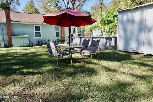 view of yard featuring an outdoor structure and outdoor dining space