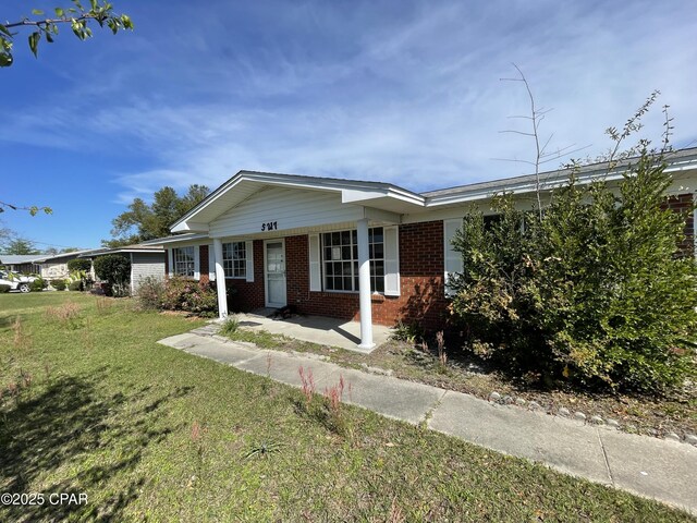 ranch-style house featuring a front lawn, covered porch, and brick siding