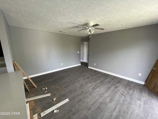 unfurnished room with dark wood finished floors, baseboards, visible vents, a ceiling fan, and a textured ceiling