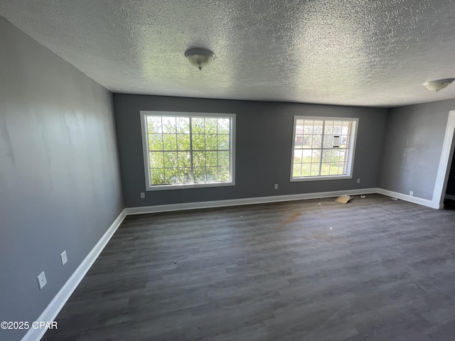 unfurnished room featuring dark wood finished floors, a textured ceiling, baseboards, and a healthy amount of sunlight