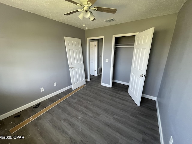 unfurnished bedroom with a closet, baseboards, visible vents, a textured ceiling, and dark wood-style floors