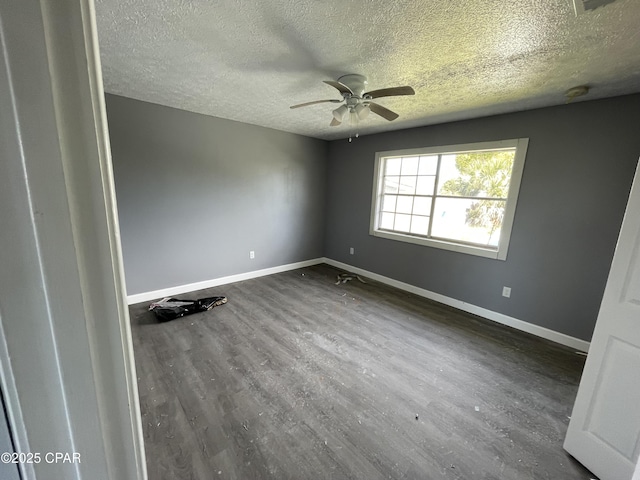 spare room featuring a textured ceiling, ceiling fan, dark wood-style flooring, and baseboards