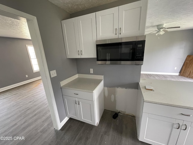 kitchen with dark wood finished floors, ceiling fan, a textured ceiling, and stainless steel microwave
