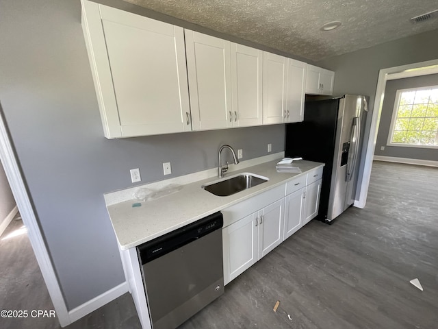 kitchen featuring appliances with stainless steel finishes, dark wood-type flooring, white cabinetry, and a sink