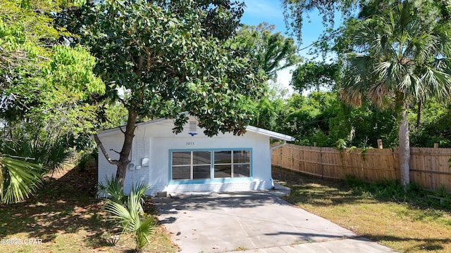view of outdoor structure featuring an outbuilding, concrete driveway, and fence
