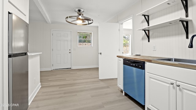 kitchen with a ceiling fan, wood counters, white cabinets, dishwashing machine, and freestanding refrigerator