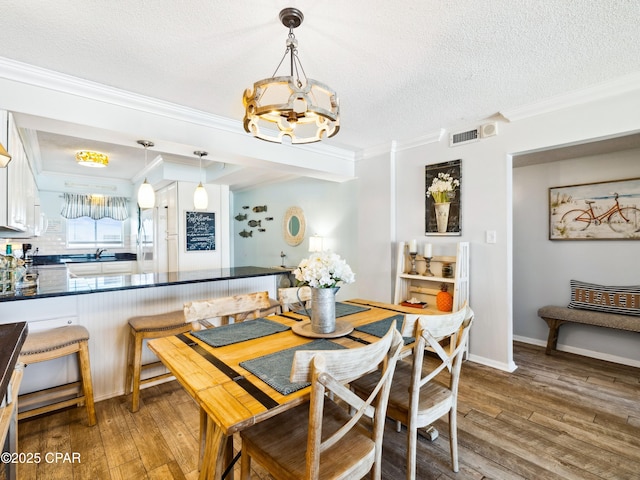 5801 Thomas Dr Unit 415, Panama City, FL 32408 - dining area with light wood finished floors, visible vents, an inviting chandelier, and crown molding
