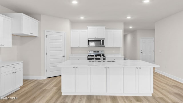 kitchen featuring stainless steel appliances, baseboards, a sink, and light wood-type flooring