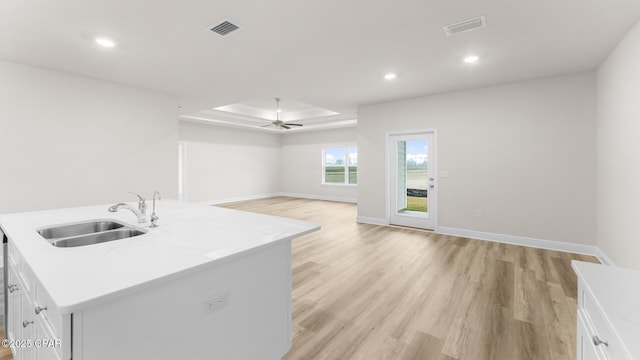 kitchen with a sink, light wood-style floors, a ceiling fan, open floor plan, and visible vents