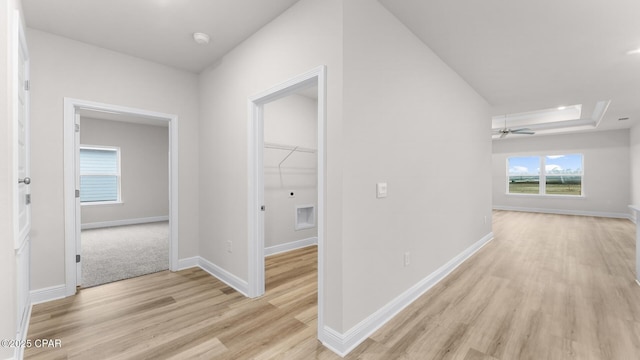 hallway featuring light wood-style floors, baseboards, and a healthy amount of sunlight