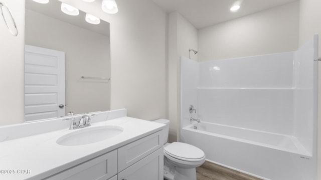 bathroom with toilet, washtub / shower combination, wood finished floors, and vanity