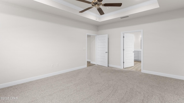 unfurnished bedroom featuring crown molding, visible vents, light carpet, baseboards, and a raised ceiling