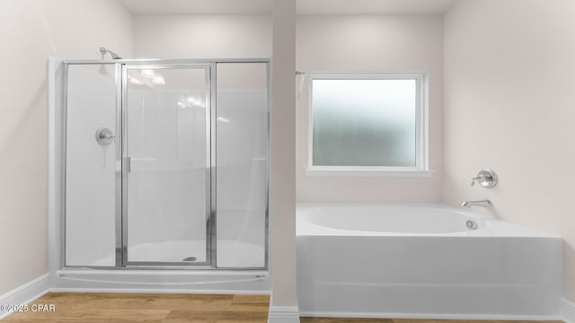 full bath with wood finished floors, a garden tub, and a stall shower