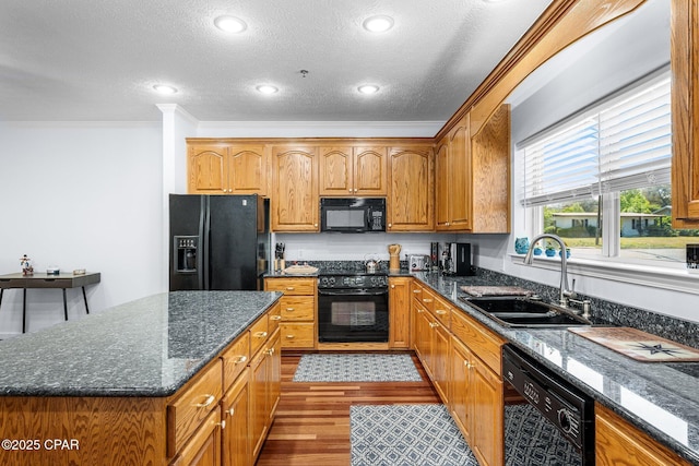 kitchen with ornamental molding, wood finished floors, a textured ceiling, a sink, and black appliances