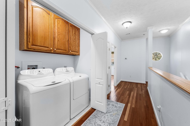 laundry area featuring crown molding, dark wood-style floors, cabinet space, and washing machine and clothes dryer