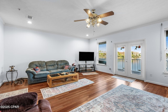 living room featuring crown molding, baseboards, a ceiling fan, and visible vents