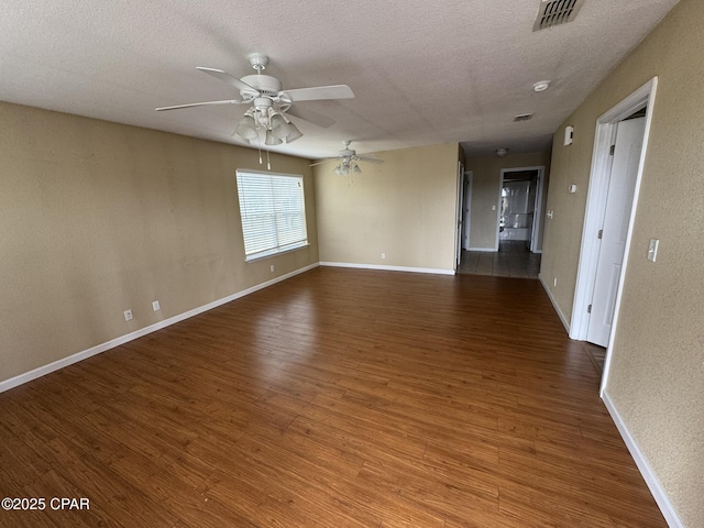 spare room featuring wood finished floors, a textured ceiling, ceiling fan, baseboards, and visible vents
