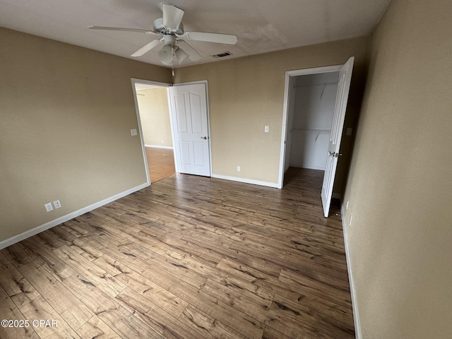unfurnished bedroom featuring baseboards, wood finished floors, visible vents, and ceiling fan