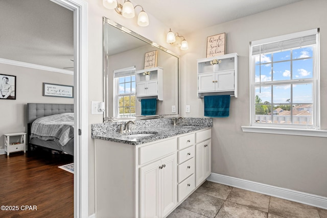 full bathroom with double vanity, baseboards, ornamental molding, and a sink