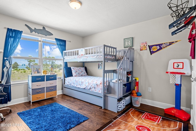 bedroom featuring baseboards, a textured ceiling, and wood finished floors