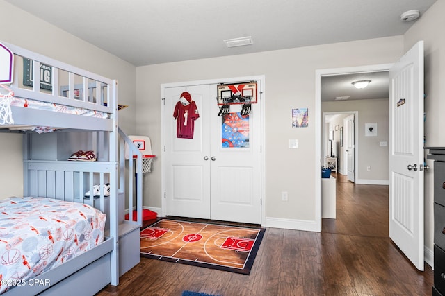 bedroom with baseboards, wood finished floors, visible vents, and a closet