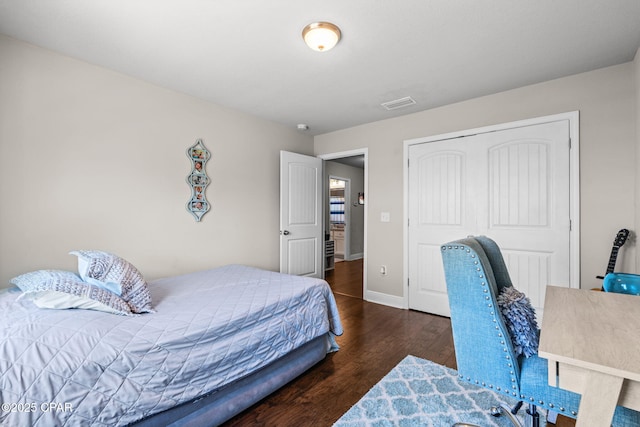 bedroom featuring baseboards, a closet, wood finished floors, and visible vents
