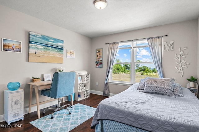 bedroom featuring baseboards, a textured ceiling, and wood finished floors