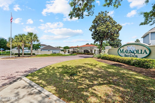 community / neighborhood sign featuring a lawn and driveway