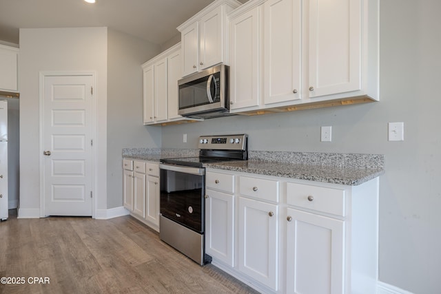 kitchen with light wood-style flooring, white cabinets, and appliances with stainless steel finishes