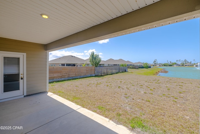 view of yard featuring a residential view, fence, a water view, and a patio area