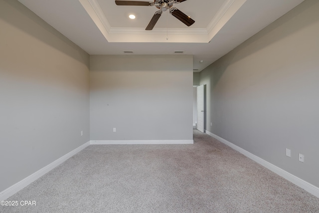 carpeted spare room with a raised ceiling, a ceiling fan, visible vents, and crown molding