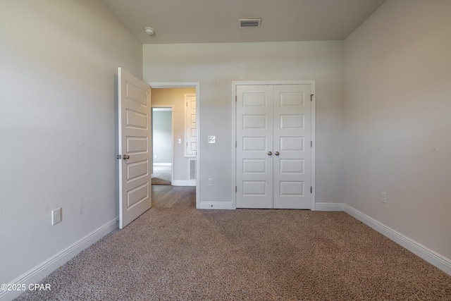 unfurnished bedroom featuring carpet, visible vents, a closet, and baseboards