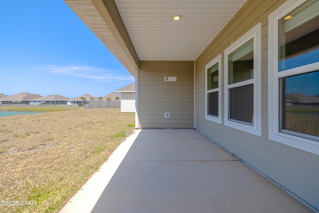 view of patio with fence and a water view