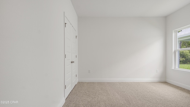 empty room with baseboards and light colored carpet